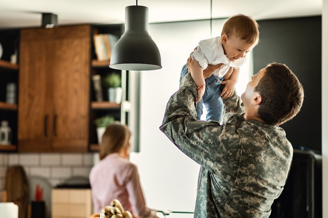 Service member holding a small child in a Colorado Springs home